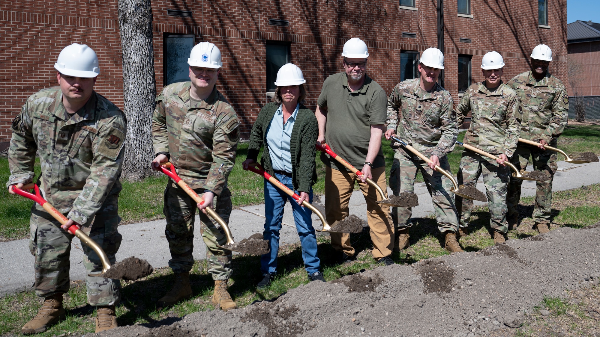 Airmen and civilians assigned to the 319th Reconnaissance Wing, 319th Civil Engineer Squadron and 319th Contracting Squadron break ground during the Bunch Hall dormitory groundbreaking ceremony at Grand Forks Air Force Base, N.D., May 7, 2025. The $14.2 million project is expected to be complete in March 2026, and will include facility upgrades to bring the 67-year old building up to modern standards. (U.S. Air Force photo by Airman Nailah Pacheco)