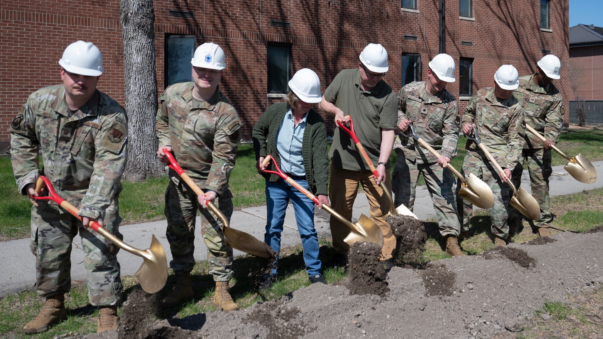 Airmen and civilians assigned to the 319th Reconnaissance Wing, 319th Civil Engineer Squadron and 319th Contracting Squadron break ground during the Bunch Hall dormitory groundbreaking ceremony at Grand Forks Air Force Base, N.D., May 7, 2025. The ceremony celebrated the start of the $14.2 million renovation project that is estimated to take a year to complete. (U.S. Air Force photo by Airman Nailah Pacheco)