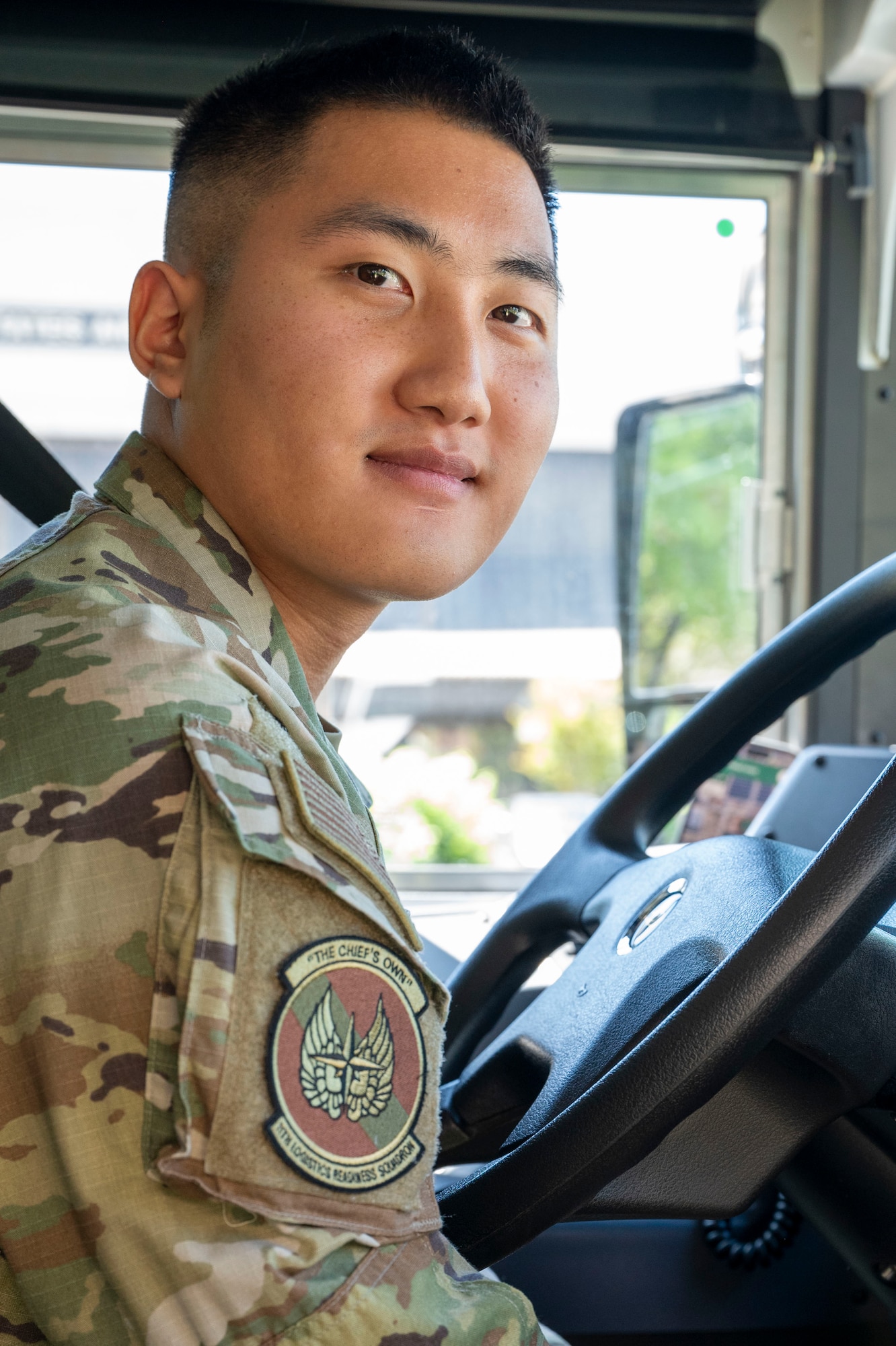 Airman leans over bus steering wheel.