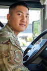 Airman leans over bus steering wheel.