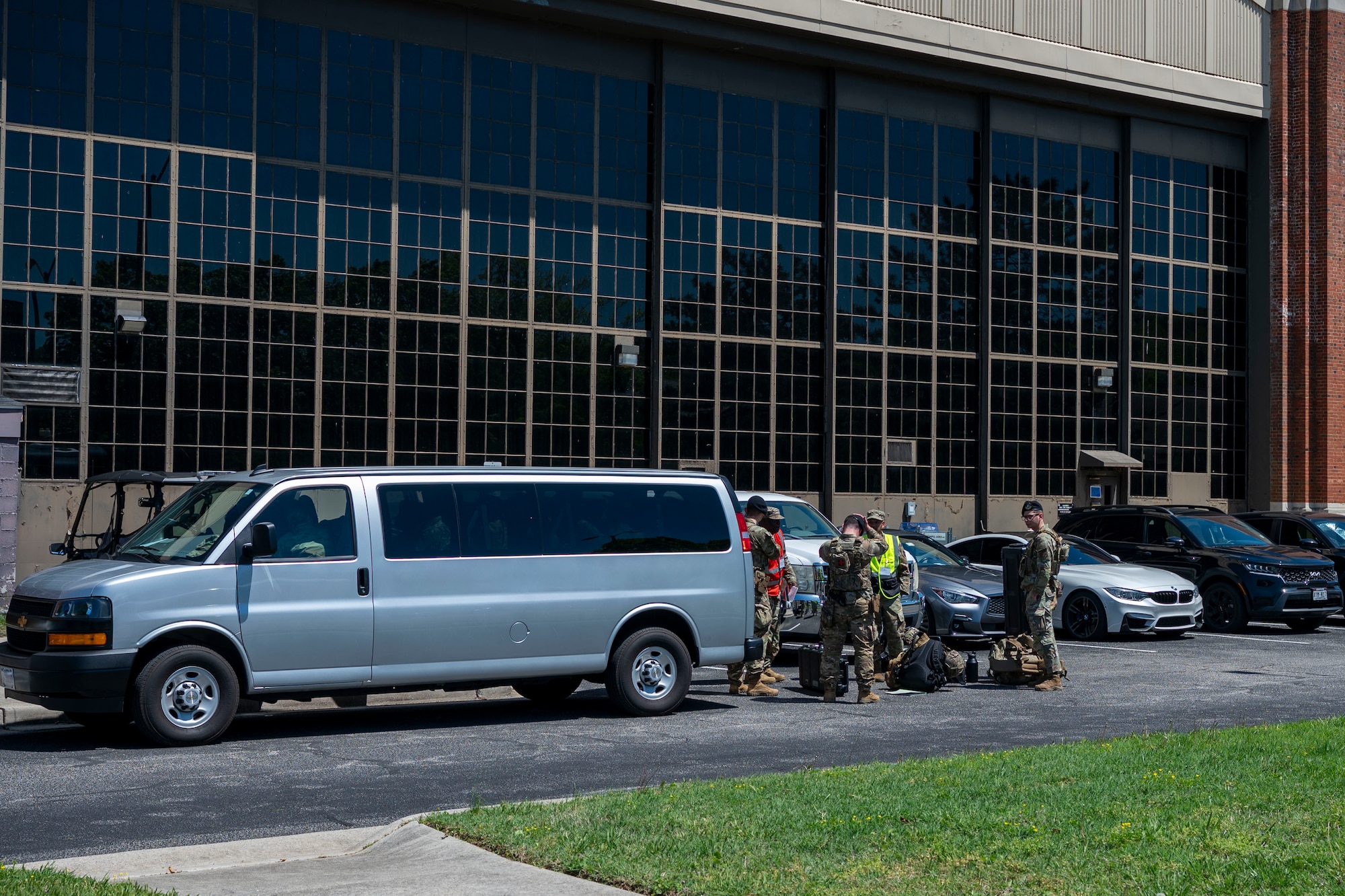 Airmen load equipment into a van outside in a parking lot.