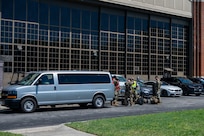 Airmen load equipment into a van outside in a parking lot.