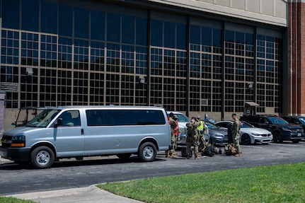Airmen load equipment into a van outside in a parking lot.
