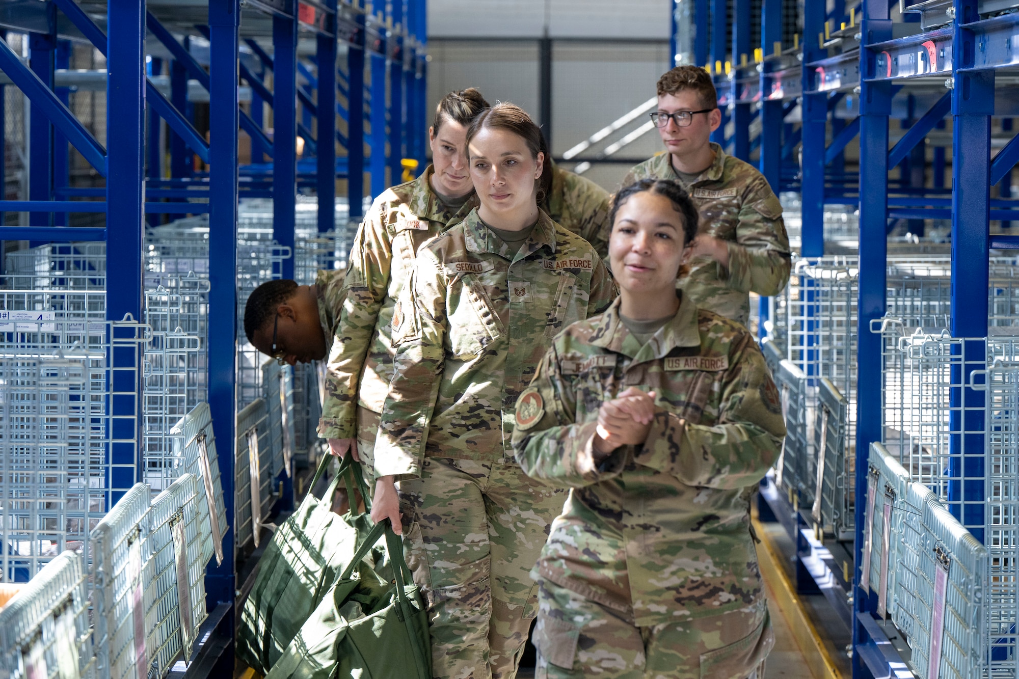 Airmen walk through wire compartments to collect issued gear.