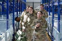 Airmen walk through wire compartments to collect issued gear.