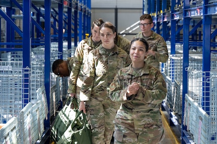 Airmen walk through wire compartments to collect issued gear.