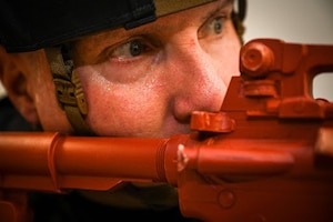 An officer wearing a tactical helmet aims a training weapon.