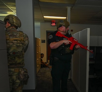 Security professionals clear office cubicles with training firearms.