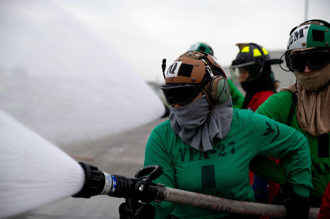 A U.S. Sailor with Strike Fighter Squadron (VFA) 27, Carrier Air Wing 5, practice extinguishing a fire a simulated fire during a firefighting training exercise at Marine Corps Air Station Iwakuni, Japan, May 9, 2025. CVW-5 Sailors are required to conduct firefighting training to practice shipboard firefighting procedures in a controlled environment prior to deploying at sea. (U.S. Marine Corps photo by Cpl. Brian Long)