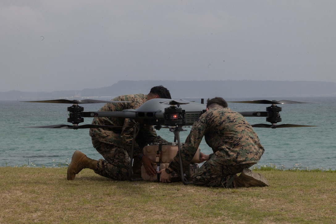 U.S. Marine Corps Lance Cpl. Anthony Rivera, left, a petroleum quality assurance Marine, and Lance Cpl. Logan Head, right, an intelligence specialist, both with Combat Logistics Battalion 31, 31st Marine Expeditionary Unit, load water supply under a Tactical Resupply Unmanned Aircraft System during a resupply exercise as part as MEU Exercise at Kin Blue Beach Training Area, Okinawa, Japan, May 8, 2025. The TRUAS is a class 3 unmanned aerial vehicle that can deliver supplies to remote and inaccessible areas. The 31st MEU, the Marine Corps’ only continuously forward deployed MEU, provides a flexible and lethal force, ready to perform a wide range of military operations as the premiere crisis response force in the Indo-Pacific region. (U.S. Marine Corps photo by Lance Cpl. Skilah Sanchez)