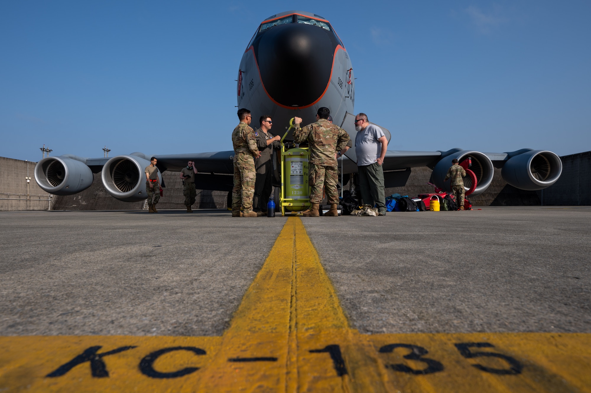 military service members stand infront of a KC-135 Stratotanker aircraft on the flightline before a flight