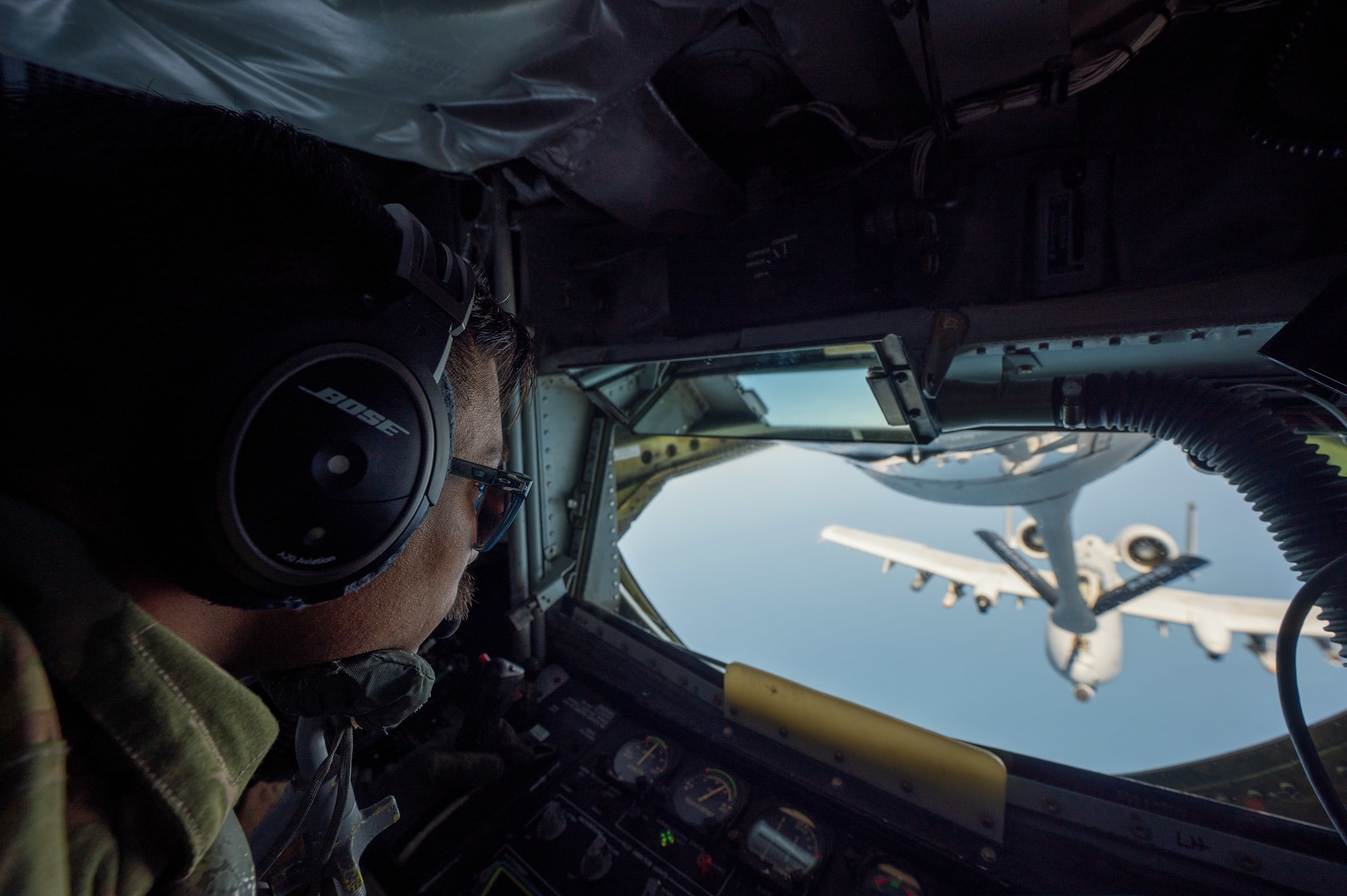 an A-10 aircraft gets refueled by another aircraft, view from inside the boom pod with a boom operator