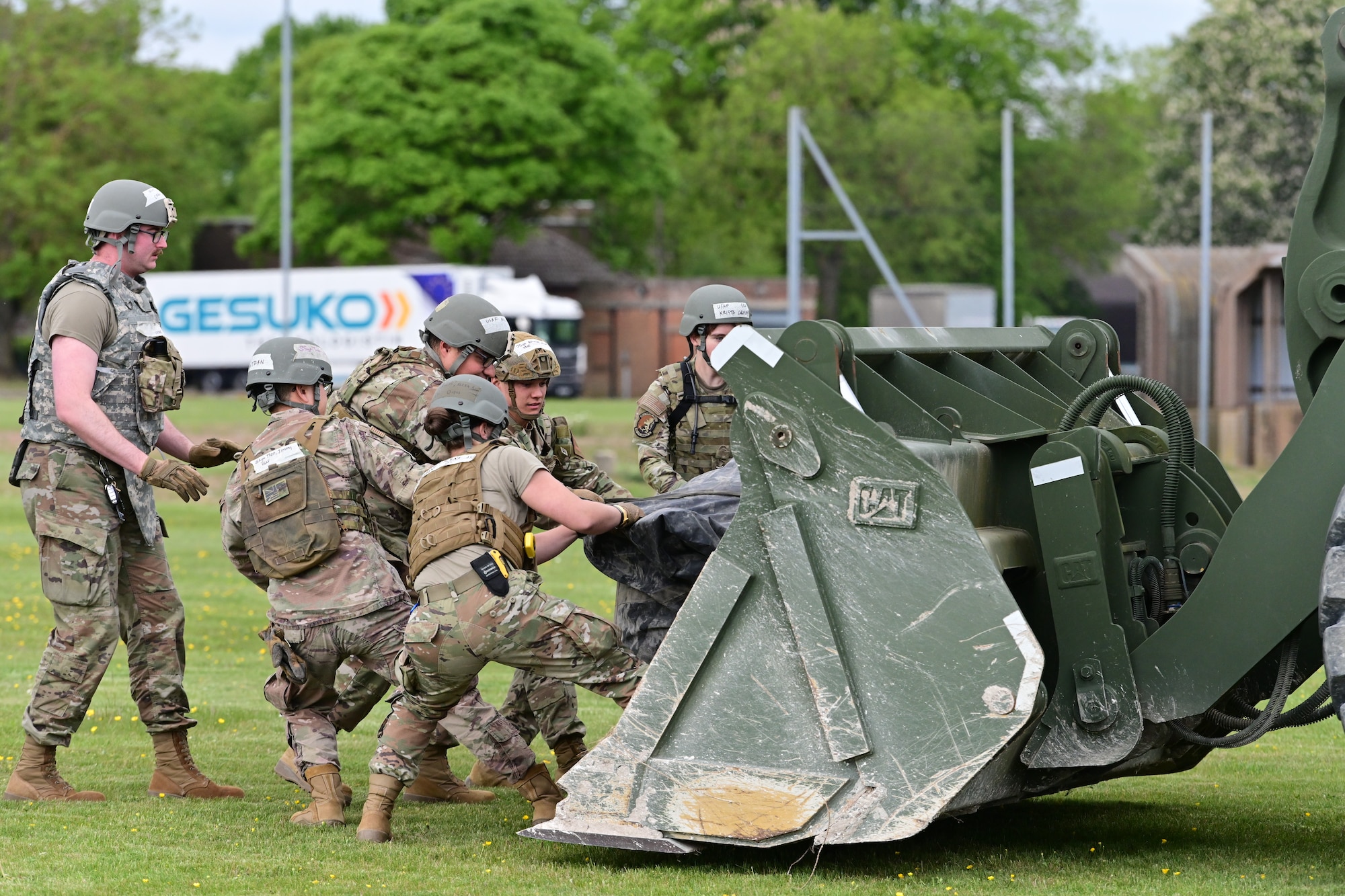 U.S. Airmen assigned to the 100th Civil Engineer Squadron pull equipment off of a tractor bucket to set up camp as part of combat readiness inspection Skyway Chariot at RAF Feltwell, England, May 8, 2025.
