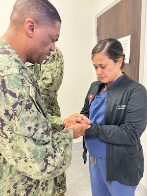 250506-N-TY711-2351 MANAMA, Bahrain (May 6, 2025)  Lieutenant Commander James Hardy, Navy Chaplain, facilitating the Blessing of the Hands for Lieutenant Commander Christine Collazo, Pediatric Nurse Practitioner, assigned to U.S. Navy Medicine Readiness and Training Unit (NMRTU) Bahrain. (U.S. Navy courtesy photo)