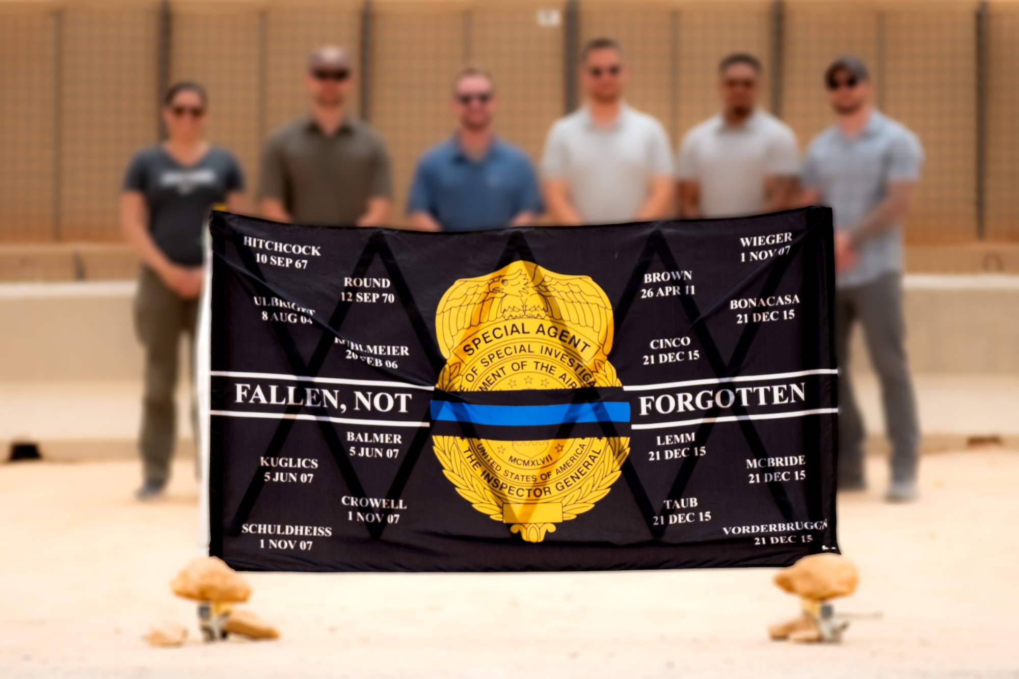 Air Force OSI investigators pose behind a memorial flag