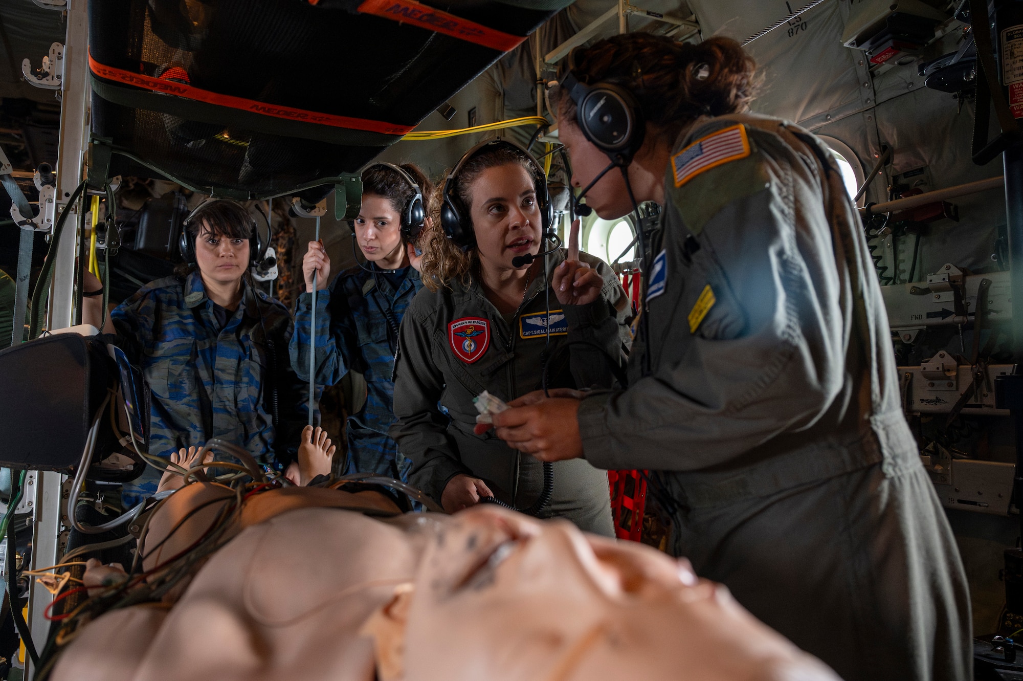 Hellenic Air Force Capt. Sigala Aikaterini, center, 251st Air Force General Hospital registered nurse, and U.S. Air Force Staff Sgt. Renata Rodriguez, right, 86th Aeromedical Evacuation Squadron AE technician, perform a medical emergency response training over Aegean Sea, Greece, during exercise Stolen Cerberus XII, May 5, 2025.