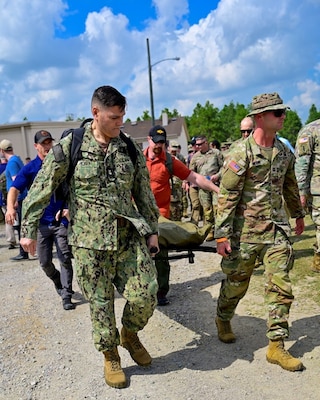 250404-N-BC658-1935 FORT BRAGG, NC (Apr. 04, 2025) Master Chief Corpsman Charles Hickey, command master chief of the Navy Medicine Operational Training Command (NMOTC)(left), carries a stretcher with a simulated patient to assist special operations medical personnel comprised of Soldiers and Sailors of the U.S. Army John F. Kennedy Special Warfare Center and School's; Joint Special Operations Medical Training Center (JSOMTC) during a mass casualty event demonstration during the CAPEX2025 exercise on Fort Bragg, North Carolina, April 4, 2025. JSOMTC provides world-class medical and skills training to special operations medical personnel of the Army, Navy and Marine Corps. (U.S. Navy photo by Mass Communication Specialist 1st Class Russell Lindsey SW/AW)