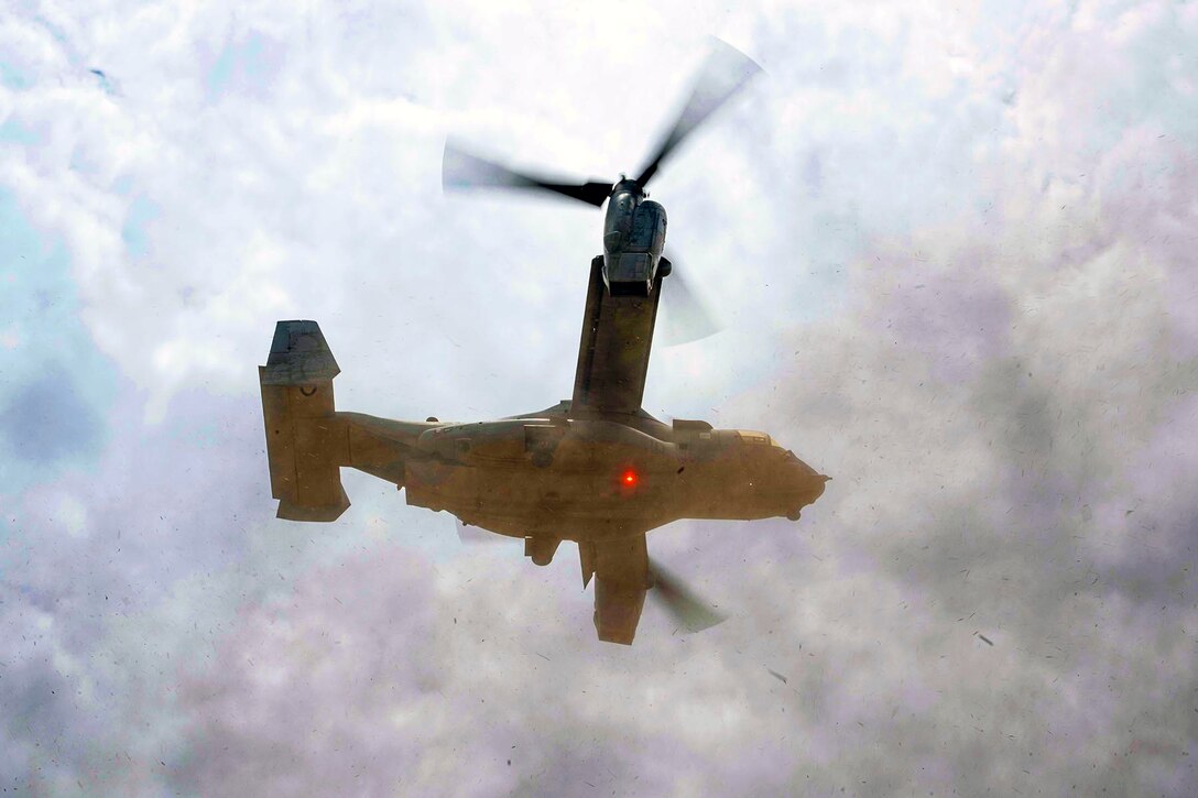 An aircraft lands as seen from below it against a cloudy sky.