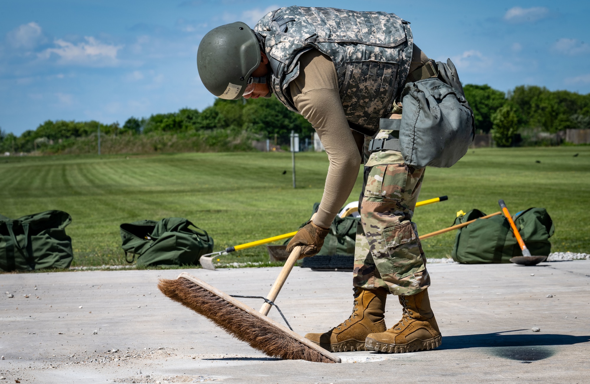 A U.S. Airman assigned to the 100th Civil Engineer Squadron uses a broom to brush away debris while repairing damage to the runway during combat readiness inspection Skyway Chariot at RAF Feltwell, England, May 9, 2025.