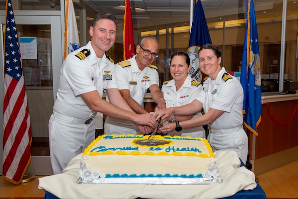 Cmdr. Rob Myslin, Naval Medical Center San Diego's Acute Psychiatry Department Head, left, Rear Adm. Guido Valdes, Commander, Naval Medical Forces Pacific, and Director, Defense Health Network Pacific Rim,  center left, Capt. Elizabeth Adriano, Director, Naval Medical Center San Diego, center right, and Cmdr. Natalie Mills, Associate Director of Nursing Services, right, cut a cake during a ribbon-cutting ceremony to celebrate the completion of NMCSD's 1 West Mental Health Ward expansion. The mission of NMCSD is to provide a superior experience for our patients, staff, and warfighters. NMCSD employs more than 5,000 active-duty military personnel, civilians, and contractors in southern California to deliver exceptional care afloat and ashore. (U.S. Navy photo by Mass Communication Specialist 2nd Class Celia Martin)