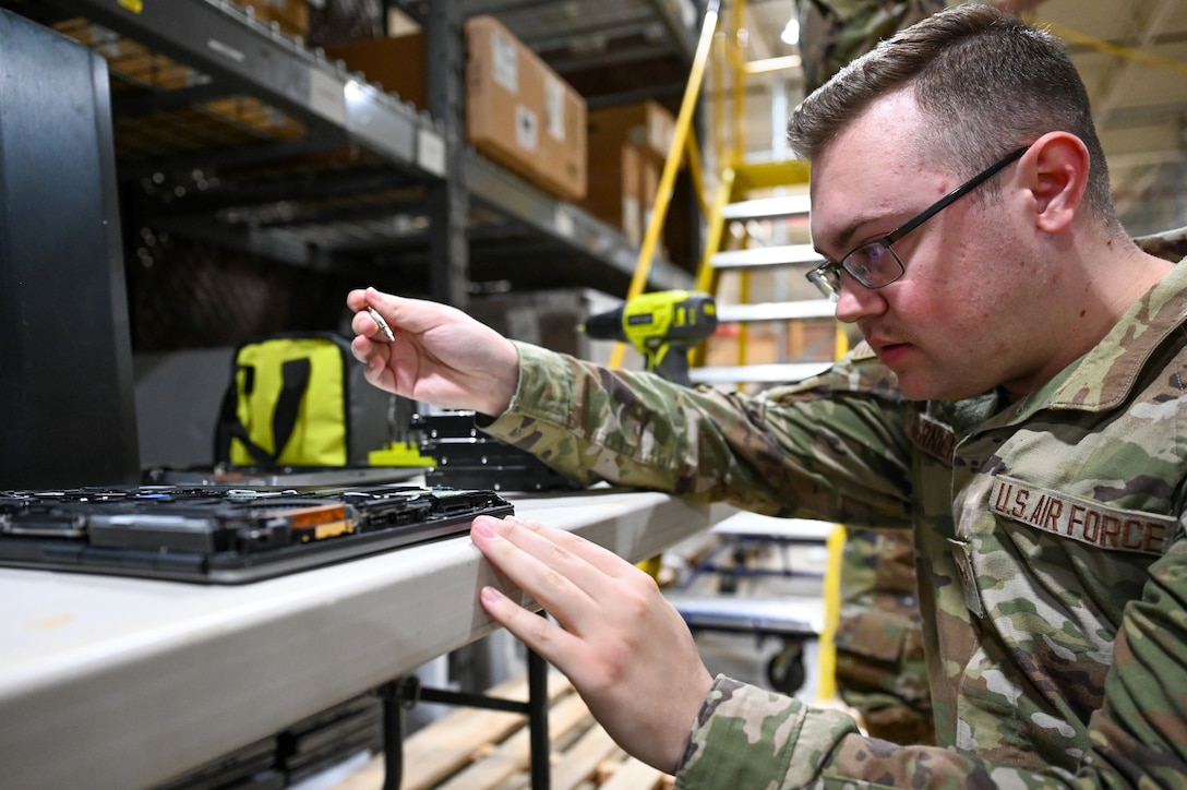 U.S. Airman deconstructs a laptop on a workbench