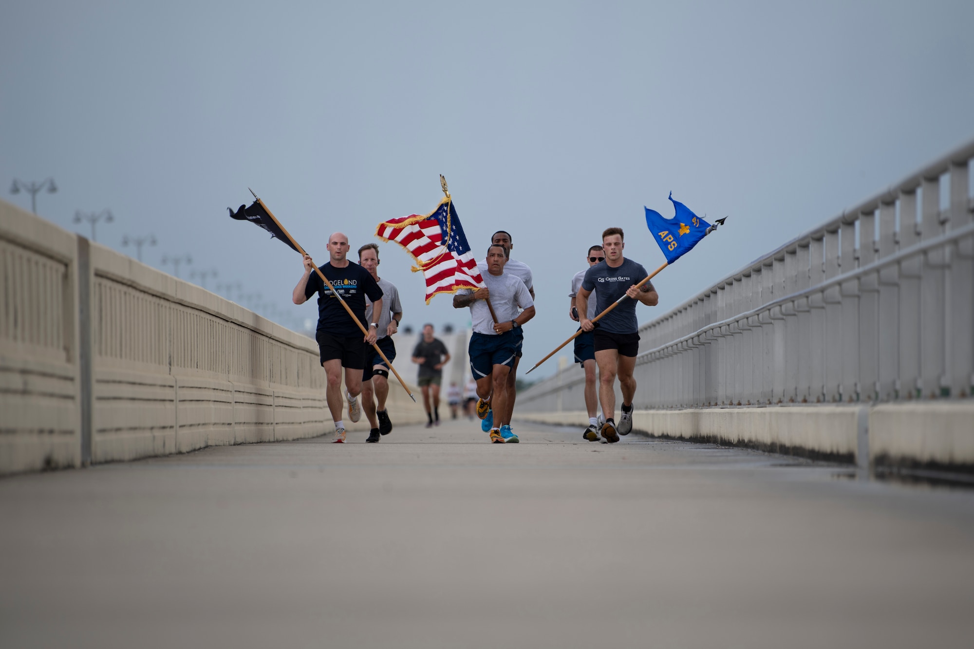 Airmen run with flags on bridge.
