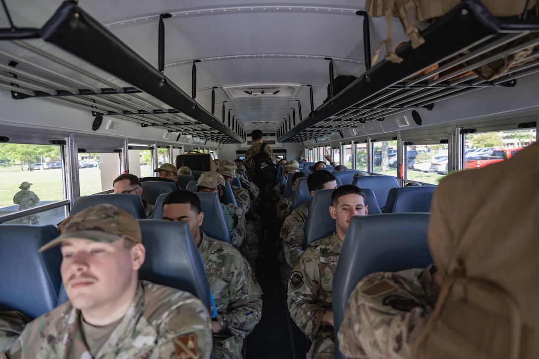 Airmen sit on a bus before leaving to go to a personnel deployment function line.
