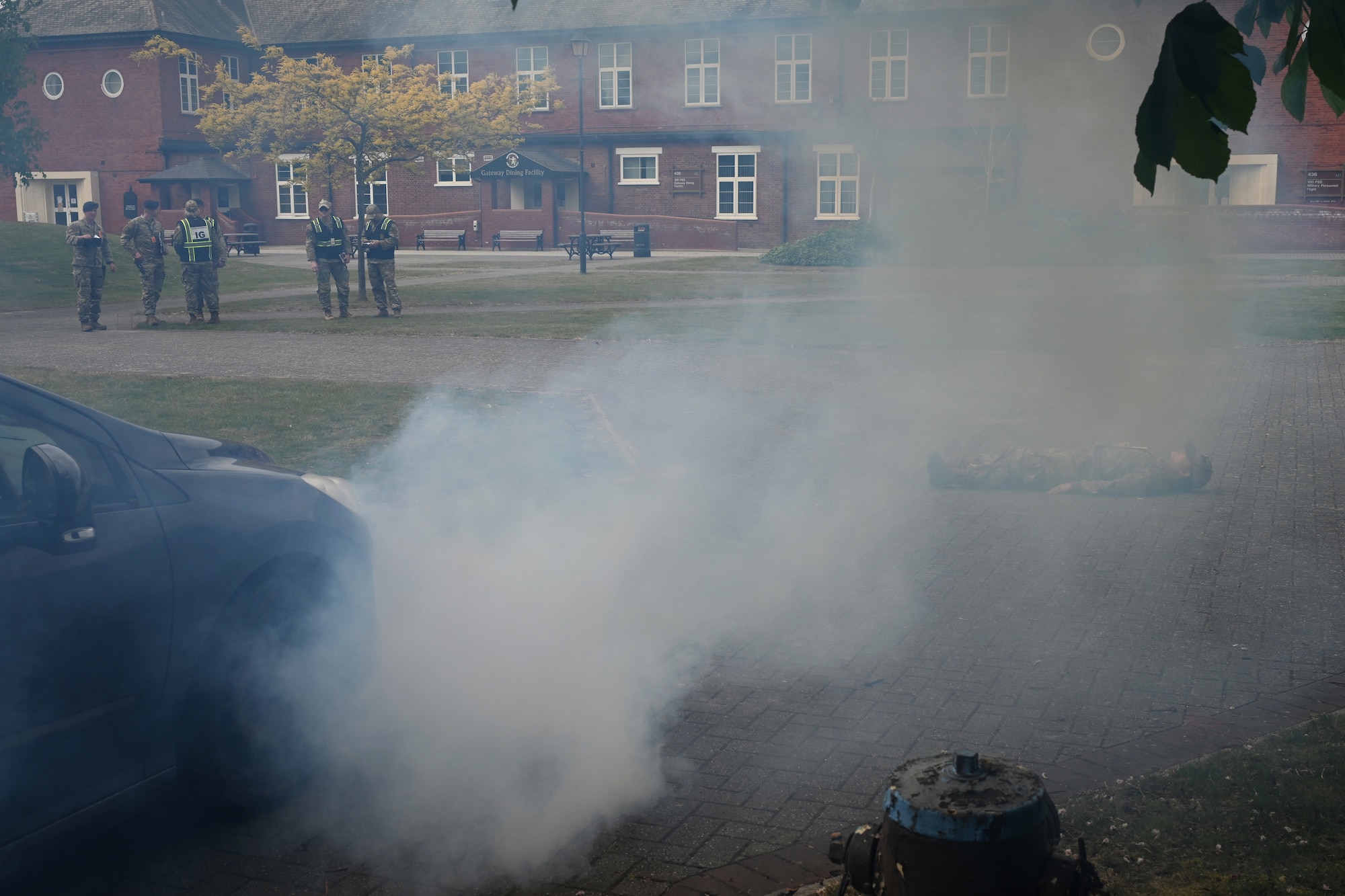 A U.S  Airman from the 100th Comptroller Squadron role plays as a casualty during a simulated vehicle-borne improvised explosive device scene as 100th Air Refueling Wing  and U.S. Air Forces in Europe Inspector General team members await the arrival of emergency responders during the combat readiness inspection Skyway Chariot at RAF Mildenhall, England, May 8, 2025.