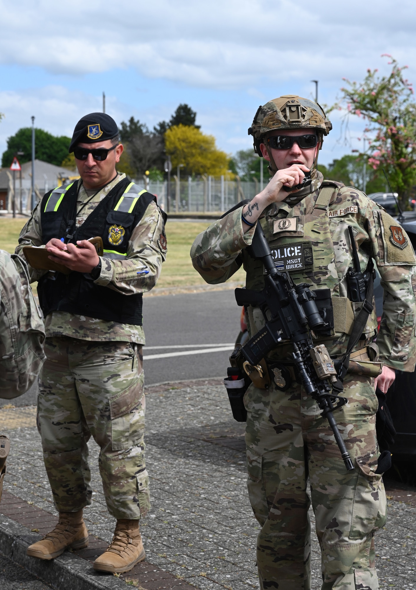 U.S. Air Force Master Sgt. Caleb Bruce, right,100th Security Forces Squadron Alpha Flight flight chief, responds to a radio call to collect more information on a simulated vehicle-borne improvised explosive device scene as a U.S. Air Forces in Europe Inspector General team member takes notes during the combat readiness inspection Skyway Chariot at RAF Mildenhall, England, May 8, 2025.