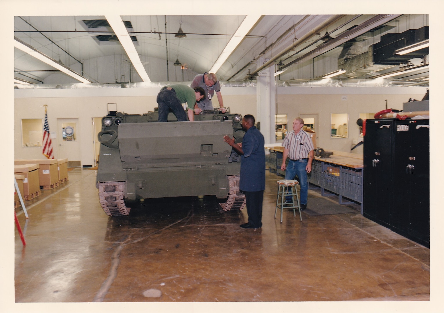 A scan of a photo from 1997 shows employees around an M113 armored personnel carrier