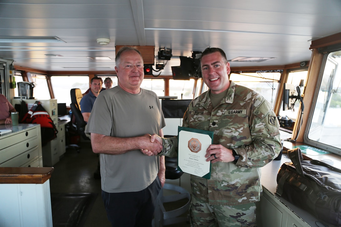Lt. Col. Kenneth M. Porter, U.S. Army Corps of Engineers, Deputy District Commander of the Wilmington District presents a 15-year ength of service award to Victor S. Nelson, USACE Dredge MURDEN master captain from the dredge Murden on April 24, 2025, in Guantanamo Bay, Cuba. The MURDEN is clearing critical shoaling by dredging areas that will maintain safe and efficient navigation conditions for military and commercial vessels in the harbor. (USACE Photo by Mark Rankin)