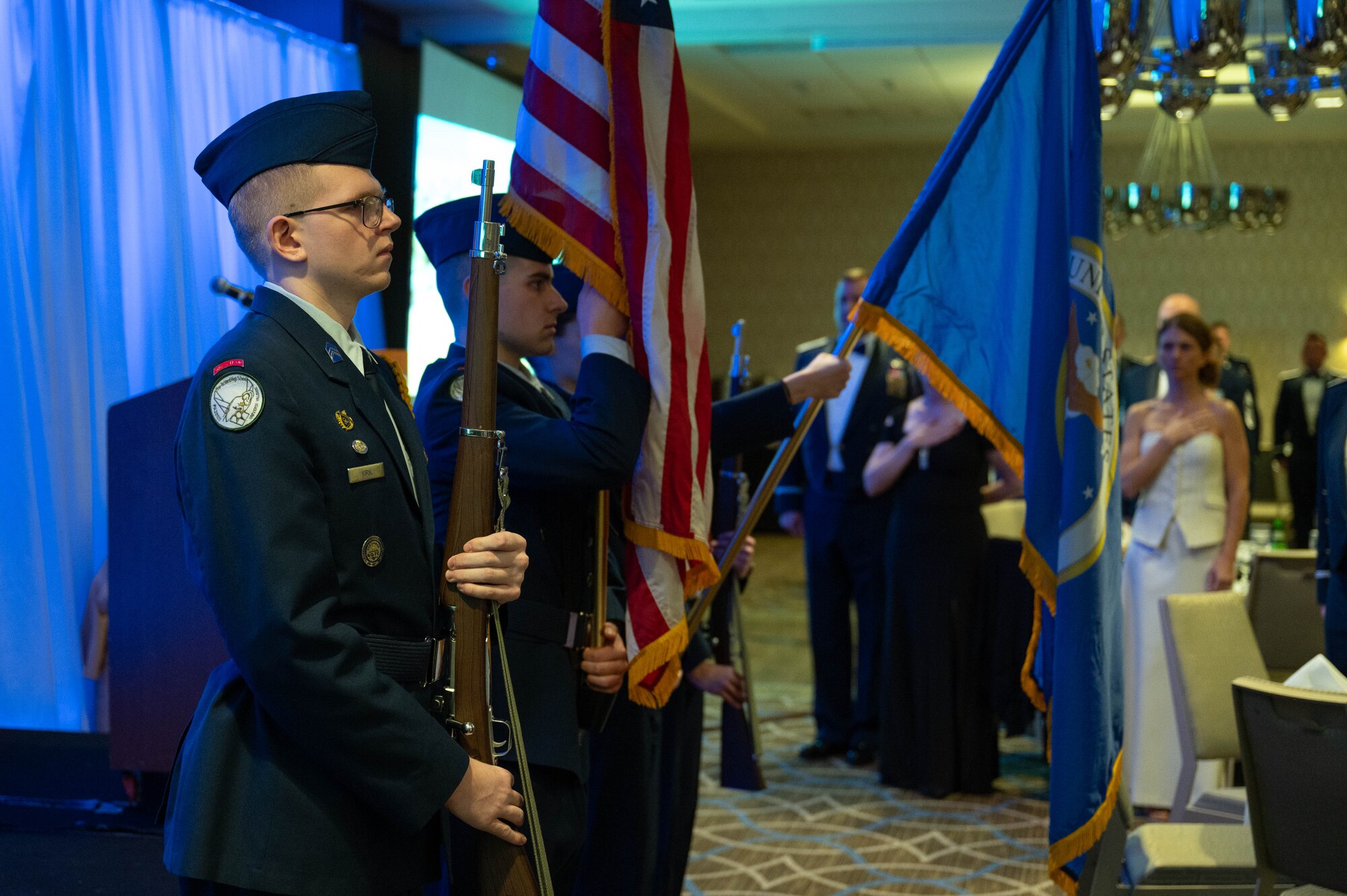 Junior ROTC color guard present the colors during the 911th Airlift Wing's 2025 Annual Awards while wearing dress blues. they carry the air force flag and the american flag