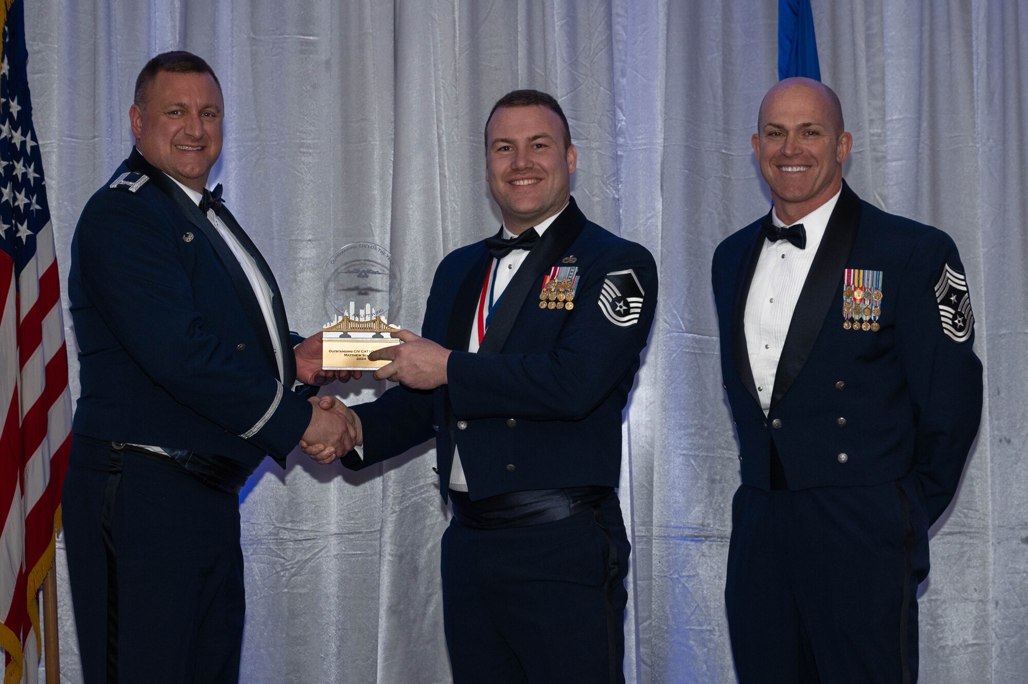 an African American male in a black tuxedo wears military medals and speaks at an awards banquet