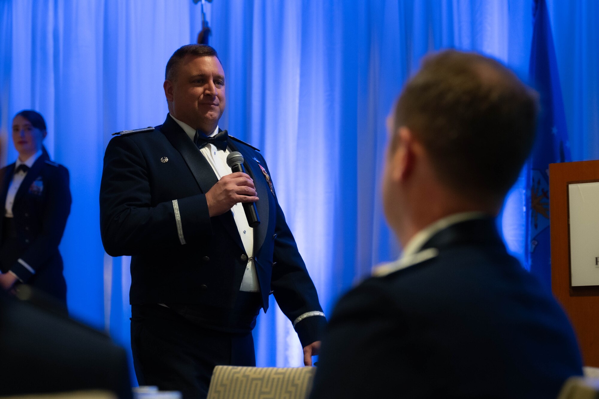 a man in a blue military suit holding a microphonespeaks at an event