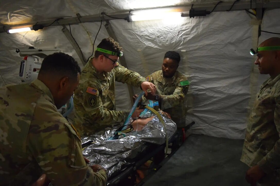 Army and Navy students in the Medical Education and Training Campus Respiratory Therapist course conduct a Joint Field Training Exercise on Joint Base San Antonio-Camp Bullis, Texas. Army Sgts. Larry Holmes, Daniel Naylor, and Darvin Peterson and Spc. Cheick Nana begin to prep a simulated patient for transport while providing continuous mechanical ventilation.