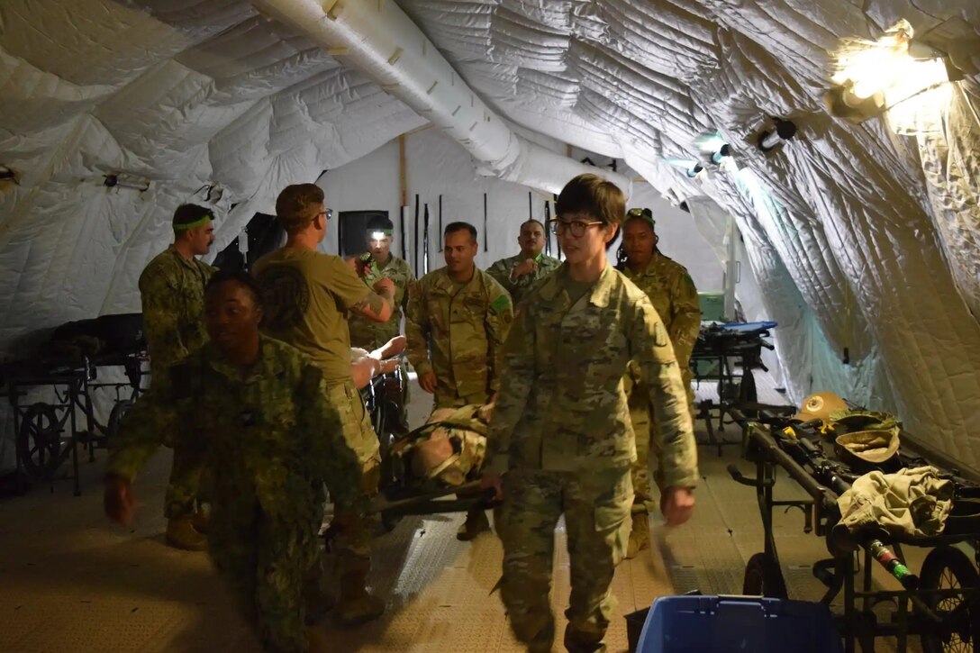 Army and Navy students in the Medical Education and Training Campus Respiratory Therapist course conduct a Joint Field Training Exercise on Joint Base San Antonio-Camp Bullis, Texas. Students bring simulated patients into the Emergency Medical Treatment tent to be treated and triaged.