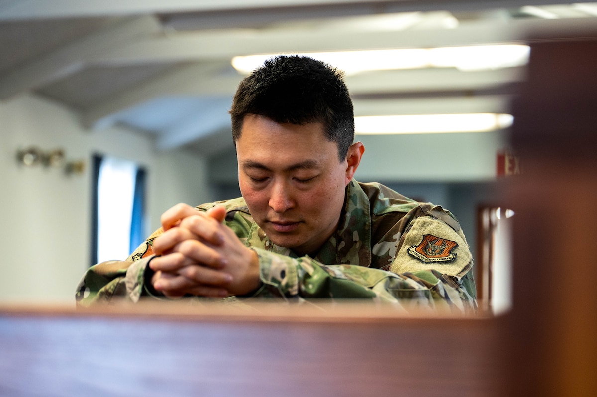 an Asian American Man wears a military uniform while praying in a chapel.