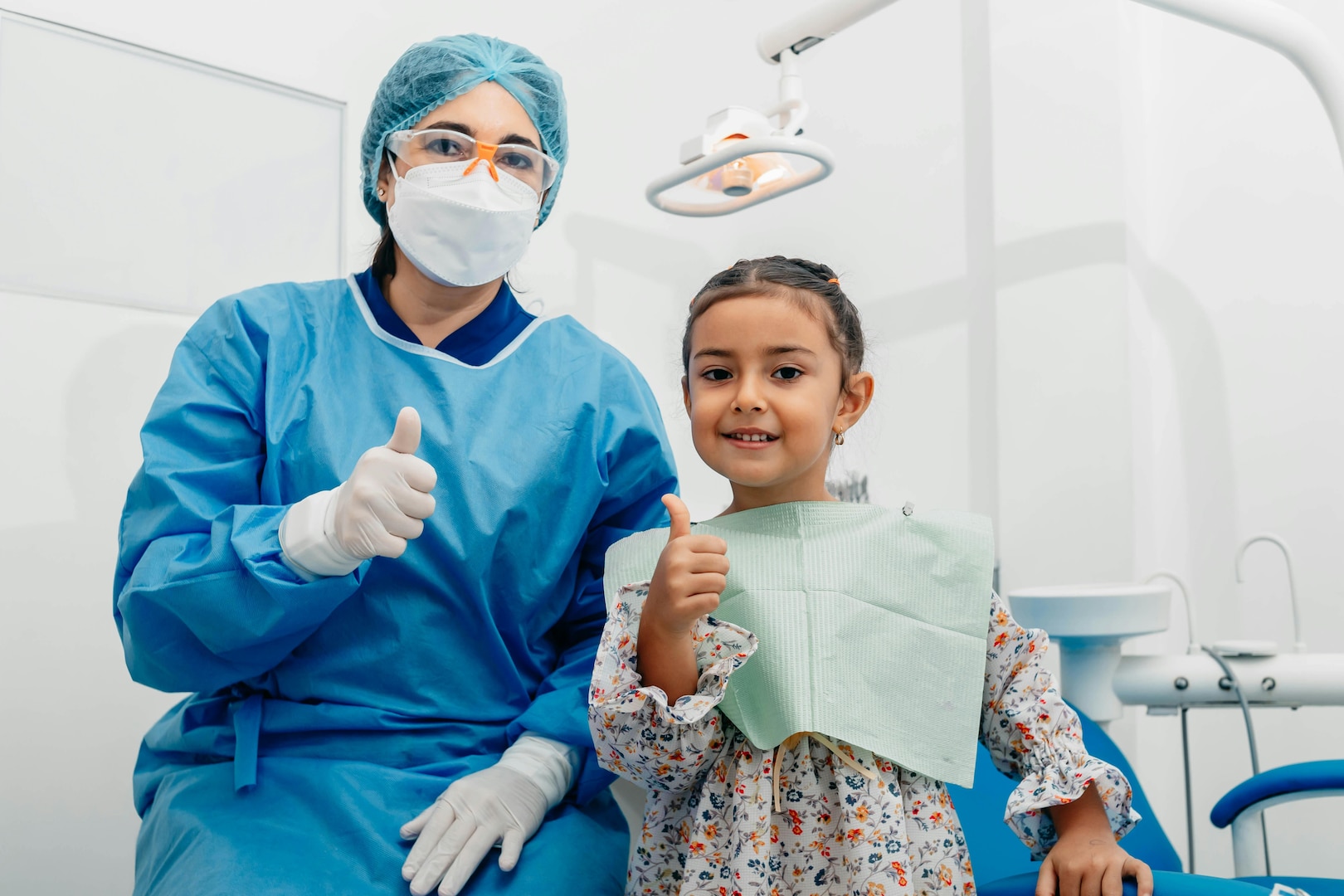 Dentist and pediatric patient give thumbs up.