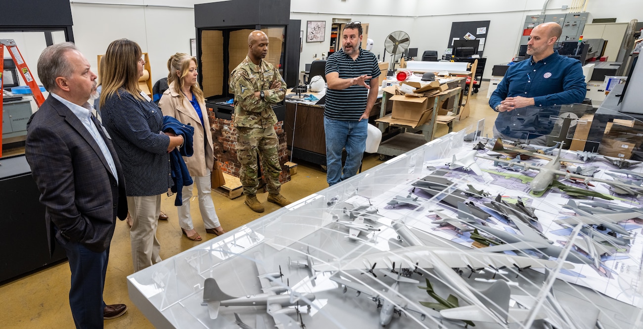 A group of people stand by a diorama of a hangar filled with model planes