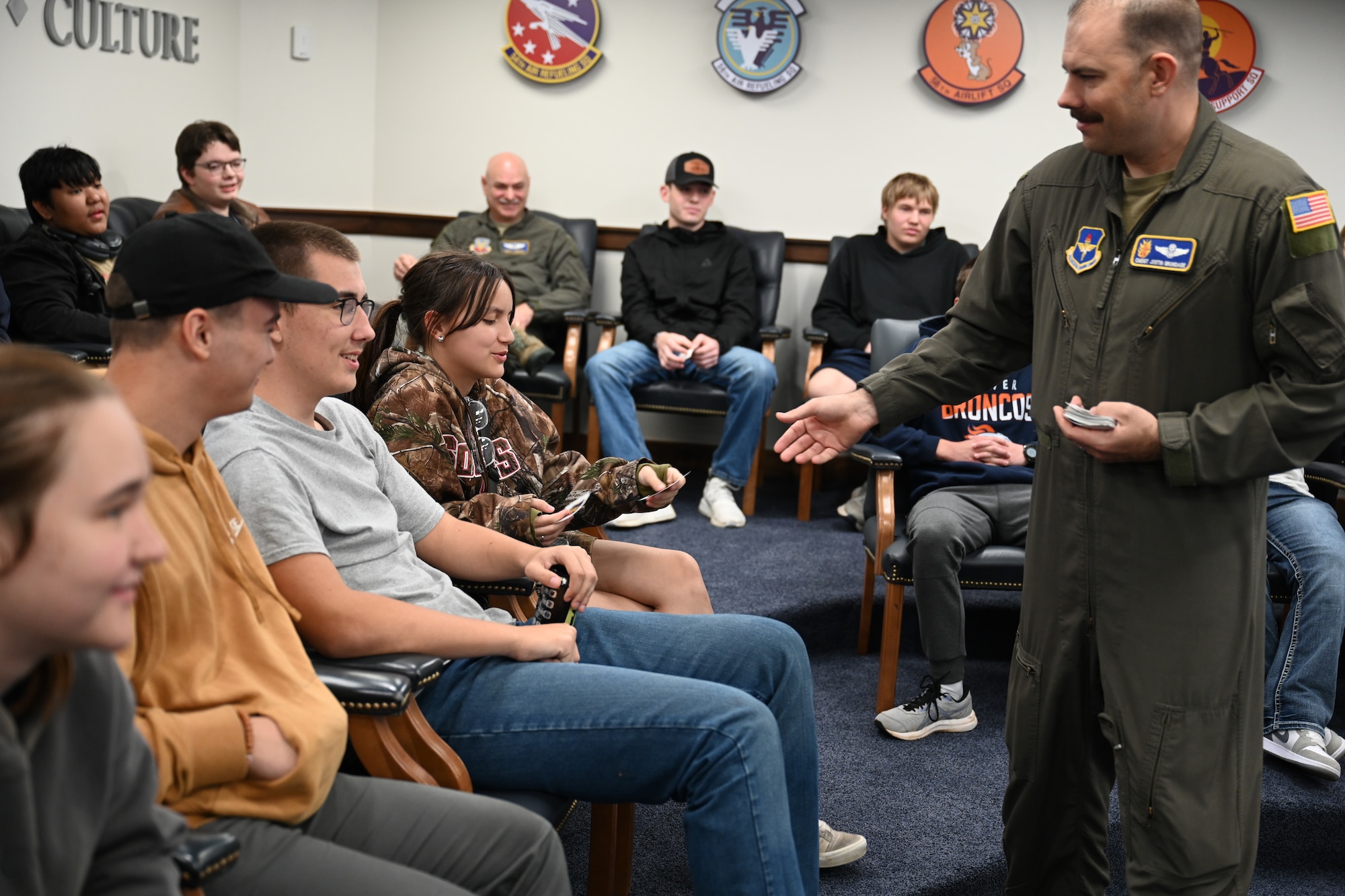 U.S. Air Force Chief Master Sgt. Justin Brundage, 97th Air Mobility Wing (AMW) command chief, hands out 97th AMW stickers during a welcome briefing for Air Force Junior ROTC (AFJROTC) students at Altus Air Force Base, Okla. on April 30, 2025. The AFJROTC Curriculum has three components: aerospace science, leadership education, and physical training. (U.S. Air Force photo by Airman 1st Class Nathan Langston)