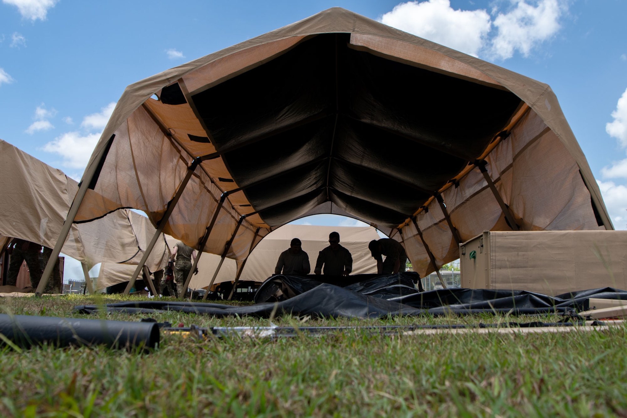 Three Airmen roll up a tent