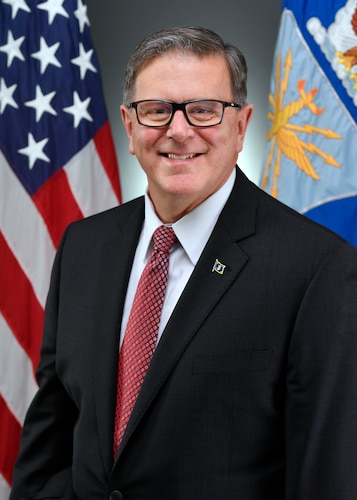 A military civilian stands for a portrait.