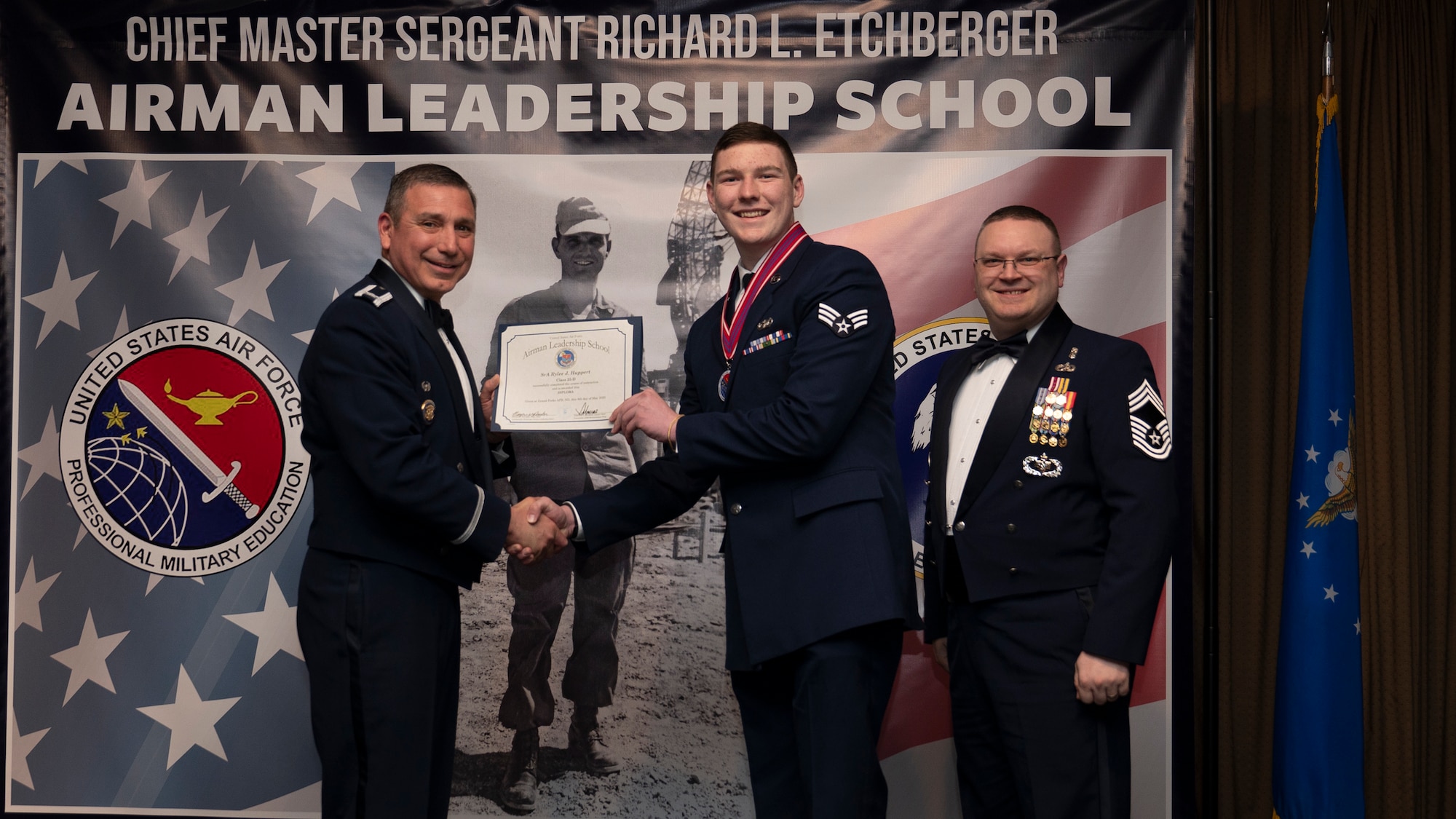Col. Reynaldo Champion, commander of the 319th Mission Support Group and Chief Master Sgt. Aaron Smith, 319th Medical Group Senior Enlisted Leader present Senior Airman Rylee J. Huppert, assigned to the 153rd Civil Engineering Squadron with an Airman Leadership School graduation certificate at Grand Forks Air Force Base, N.D., May 8, 2025. (U.S. Air Force photo by Airman Nailah Pacheco)