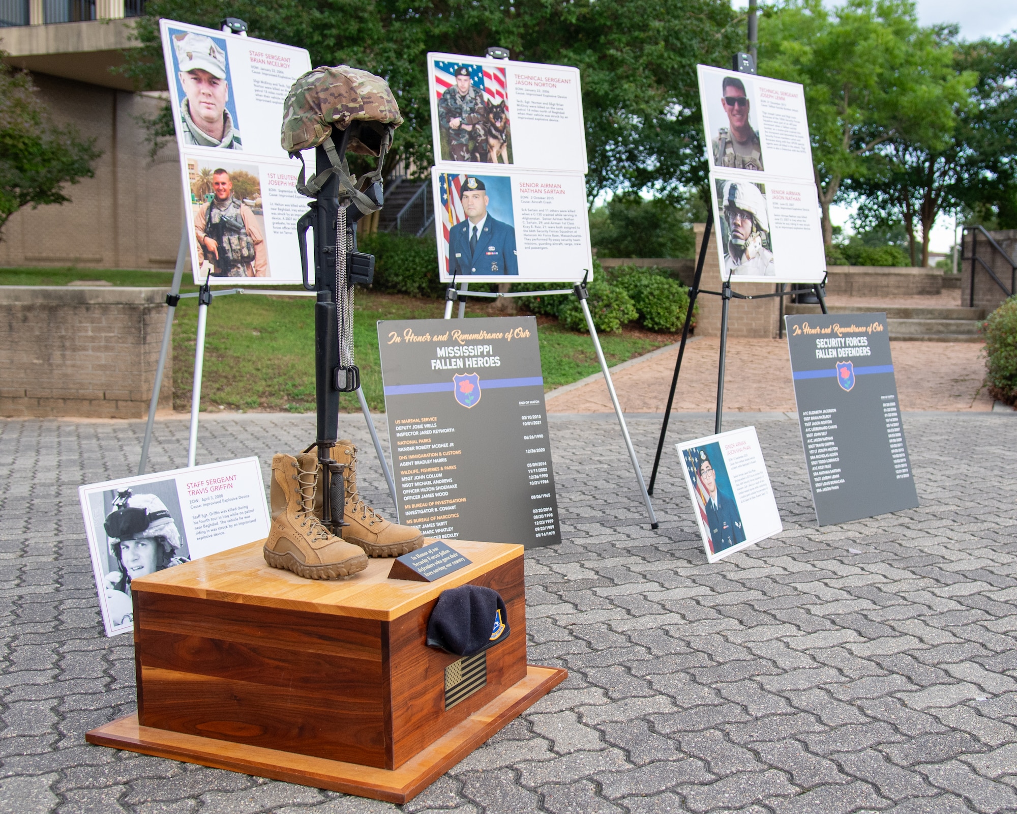 A memorial displays fallen Defenders with a Battlefield Cross in front of it.