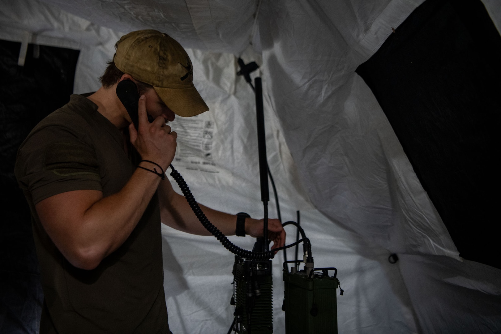 A man answers a radio call inside a tent