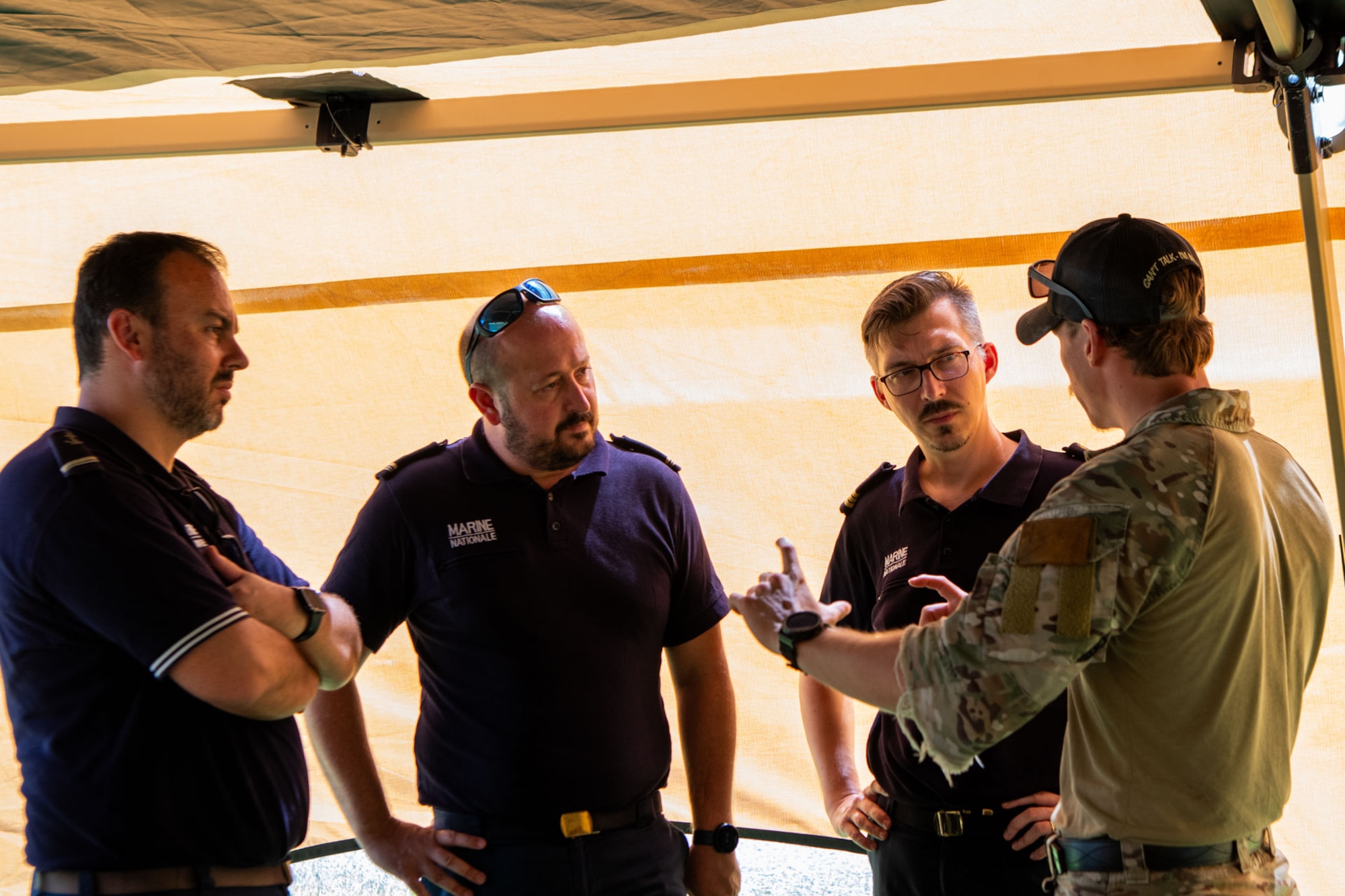 Four men talk in a circle, one uses hand gestures.