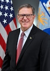 A military civilian stands for a portrait.