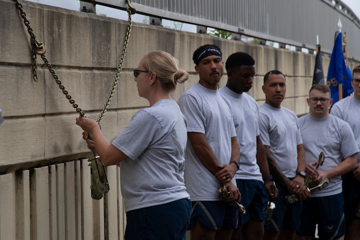 Airman hanging tie down device on chain off bridge