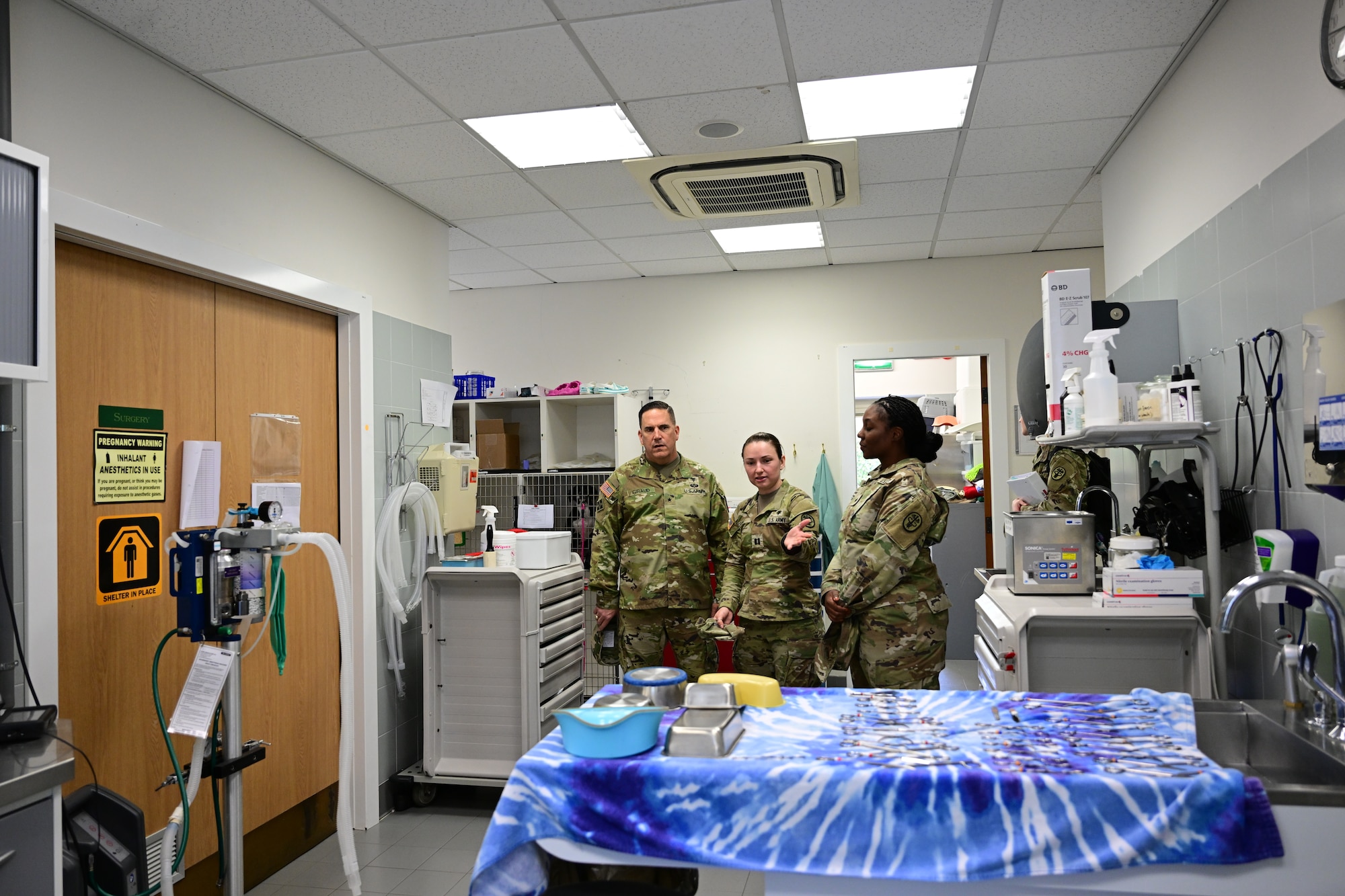 Three U.S. Army soldiers tour a vet clinic.