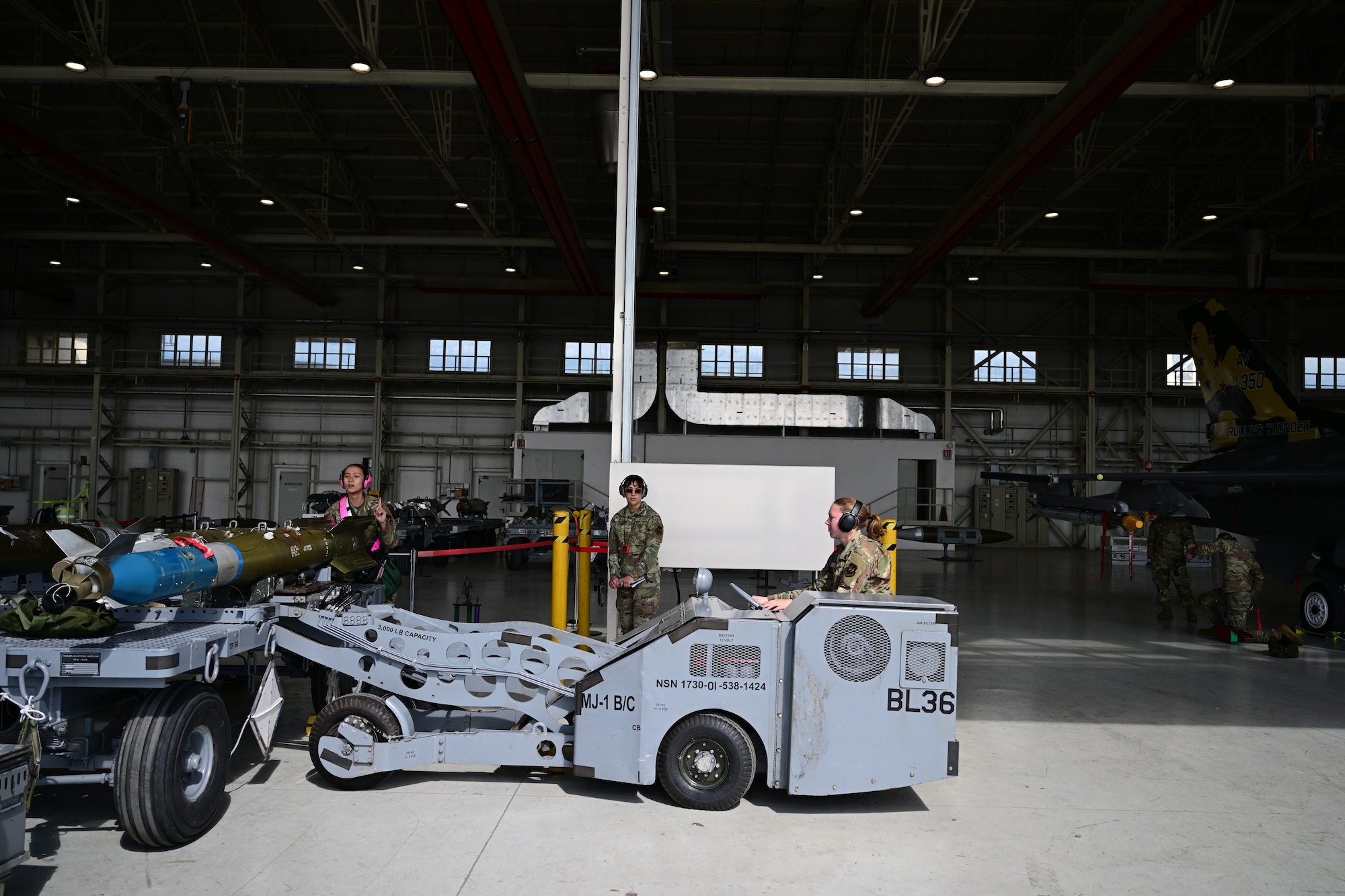 U.S. Airmen prepare to load weapon onto aircraft.